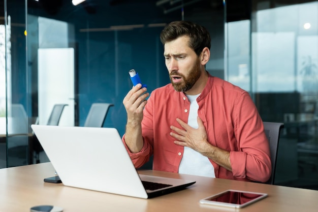 Asthma und Atemprobleme bei Büroangestellten, reifer Mann, der hustet und Medikamente im Inhalator verwendet