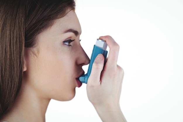 Foto asthmatischer brunette, der ihren inhalator verwendet