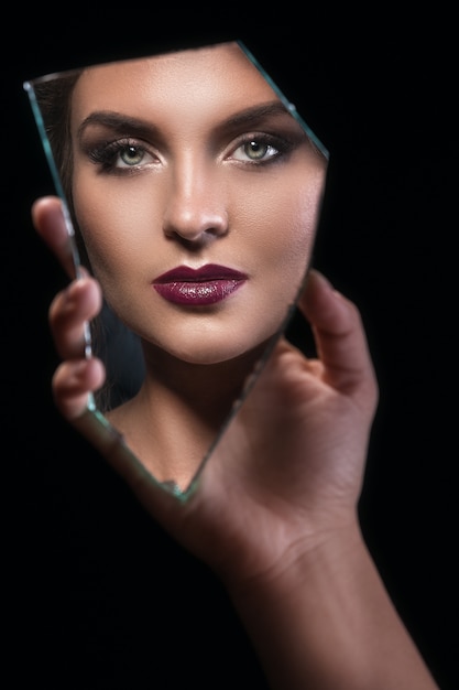 Astilla de espejo con rostro femenino en reflejo