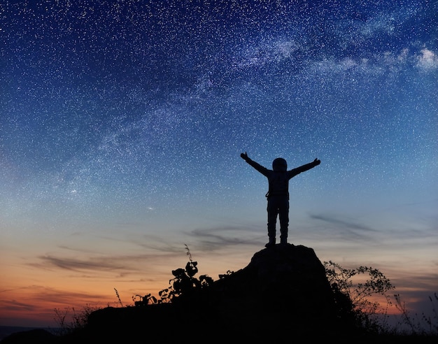 Astronaut, der auf dem Berg unter dem Nachthimmel steht