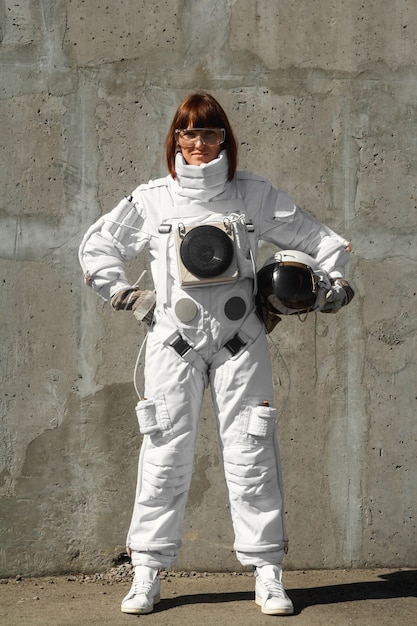 Foto astronauta de linda garota sem capacete no fundo de uma parede cinza. traje espacial fantástico.