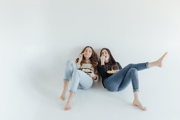 Asustadas conmocionadas mujeres jóvenes amigas viendo películas sostener un cubo de palomitas de maíz