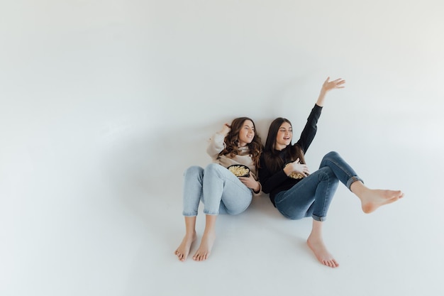 Asustadas conmocionadas mujeres jóvenes amigas viendo películas sostener un cubo de palomitas de maíz