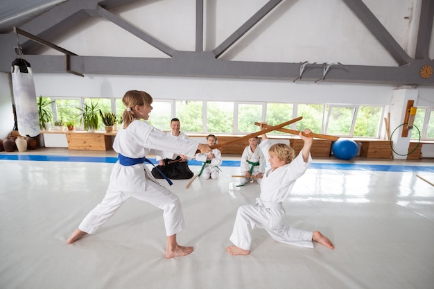 Atacando com jo. menina vestindo quimono branco atacando menino com jo enquanto aprende aikido