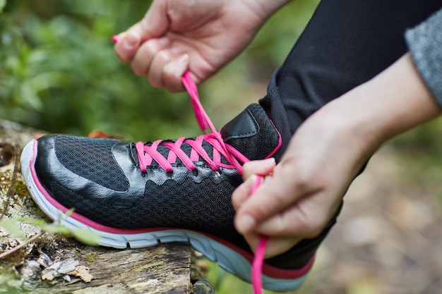 Atado y listo para ir Toma de una mujer joven no identificable atándose los cordones de los zapatos mientras camina por el bosque