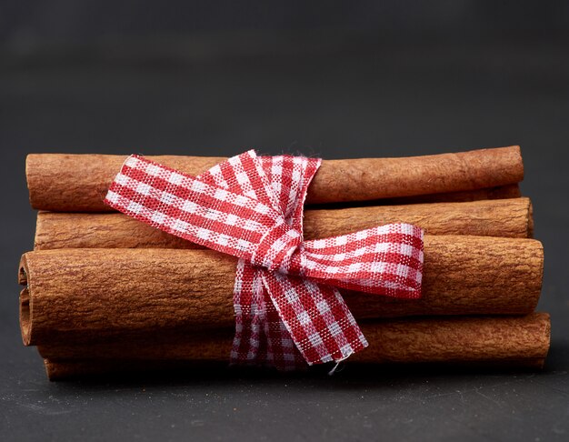 Atado manojo de palitos de canela marrón sobre un fondo oscuro