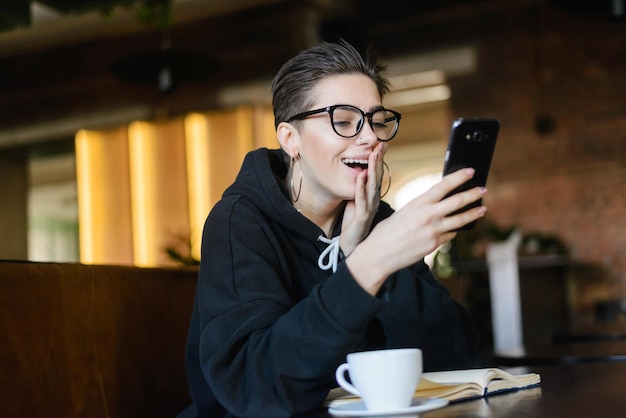 Atalho hipster jovem blogueira lendo notícias chocadas em mensagem no celular