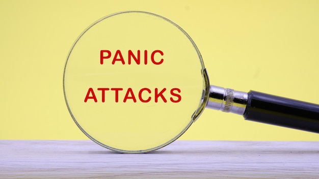 Ataques de pánico primer plano de texto a través de una lupa sobre un fondo amarillo