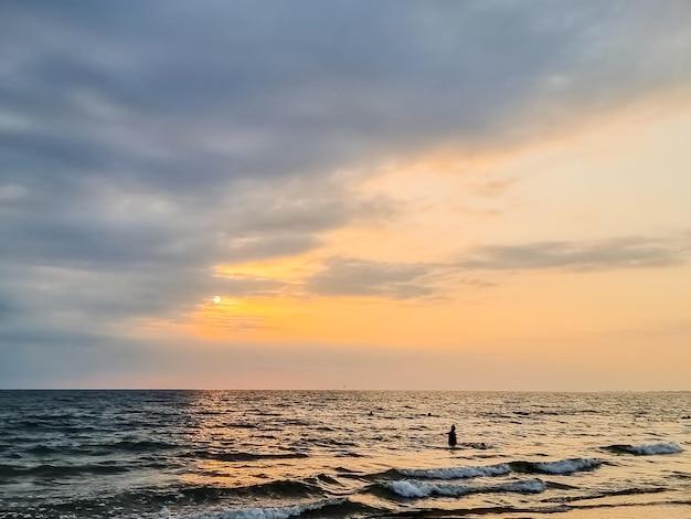 Atardecer en el cielo de reflexión de la costa y paisaje amarillo de la luz del sol durante el horizonte del paisaje marino tranquilo del atardecer