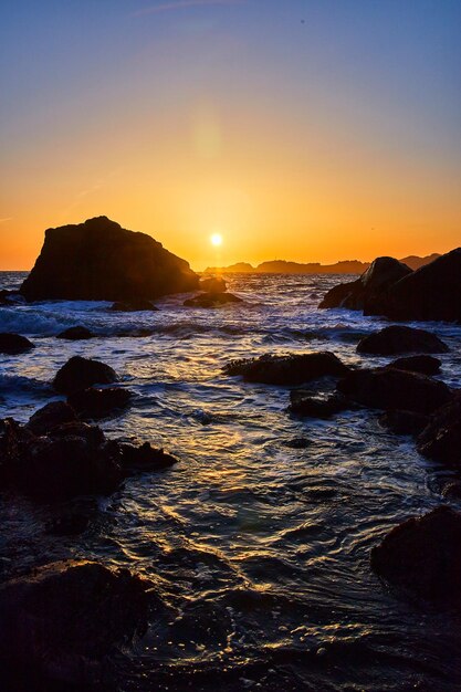 Atardecer en la costa oeste en la playa con rocas