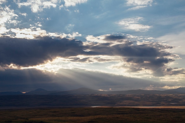 Atardecer en el desierto, los rayos del sol brillan a través de las nubes