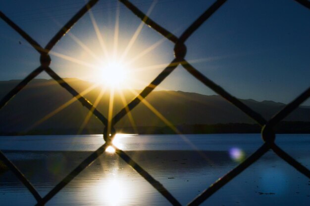 Atardecer en un lago tras una malla metalica