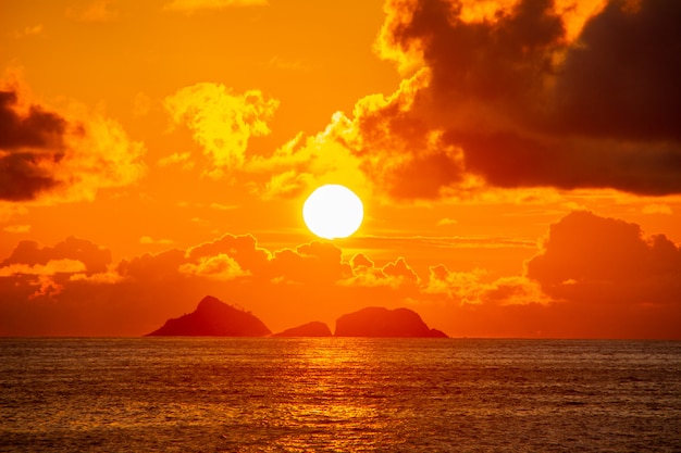 Foto atardecer en ipanema con cielo naranja y nubes.