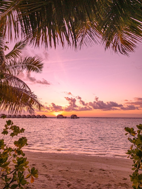 Atardecer en la isla de Maldivas, resort de lujosas villas acuáticas y muelle de madera. Hermoso cielo y nubes