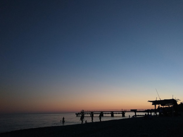 Atardecer en el mar Azul naranja Contrastes de gente y muelle