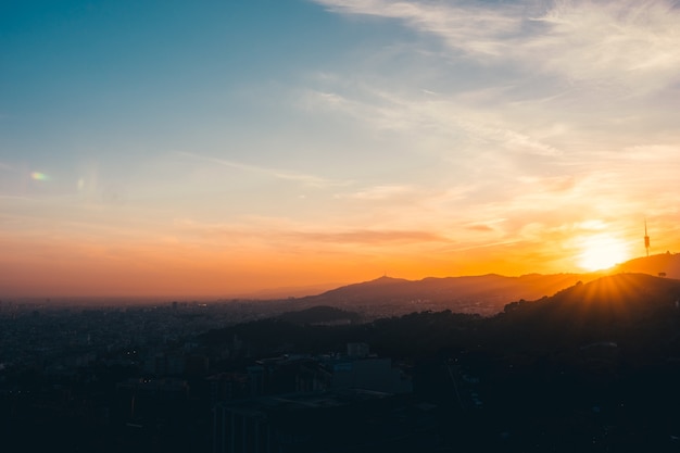 Un atardecer en la montaña con la ciudad de barcelona