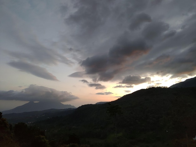 Un atardecer con nubes y montañas al fondo