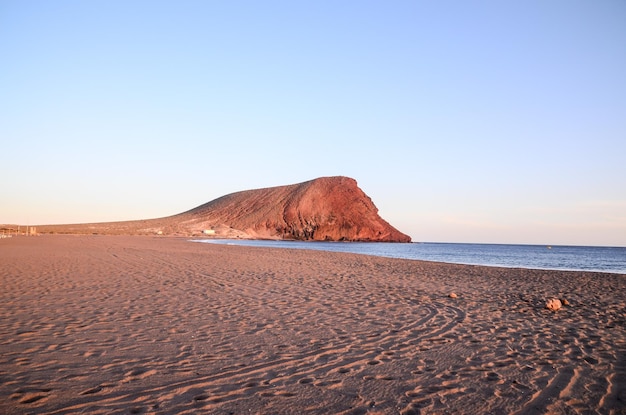 Foto atardecer en el océano atlántico con una montaña de fondo el médano tenerife islas canarias españa