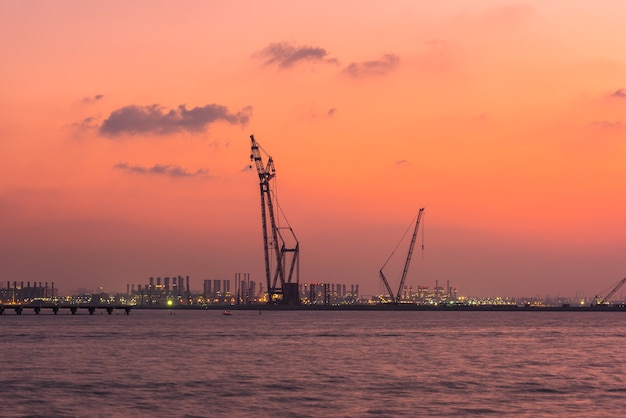 Atardecer en el puerto de Dubai, Emiratos Árabes Unidos. Silueta de grúas sobre un fondo de cielo brillante