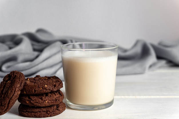 Atascado de galletas de chocolate brownie y vaso de leche de coco sobre fondo de madera. Pastelería casera