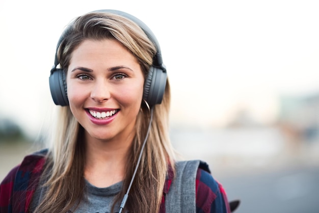 Atasco en la ciudad Retrato de una mujer joven y atractiva con auriculares mientras camina por la ciudad