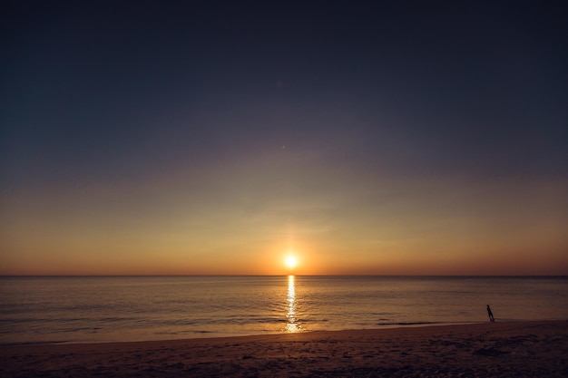 Atemberaubende Aussicht auf den Sonnenuntergang im Sommer am Strand. Wunderbare Sonnenuntergangslandschaft am tiefen dunklen Meer und orangefarbenem Himmel darüber und ruhige Wellen fließen darauf.