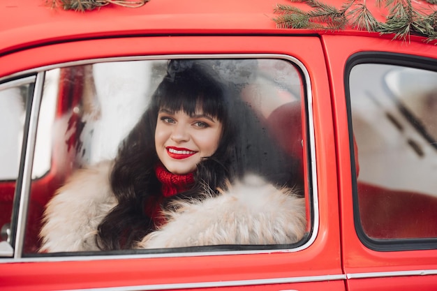 Atemberaubende Frau mit rotem Lippenstift in einem roten Auto