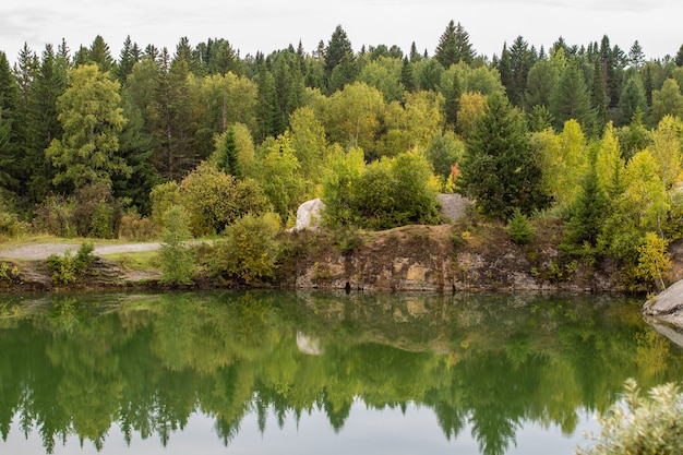 Atemberaubendes Foto von Herbstlaub, das auf einem See mit einer glasähnlichen Spiegelwasseroberfläche reflektiert wird.