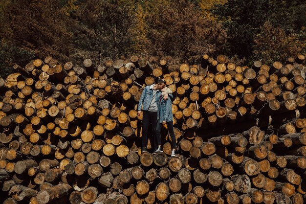 Atemberaubendes sinnliches Foto im Freien des Paares, das auf dem Brennholzstapel im schönen bunten Herbstwald küsst und steht.