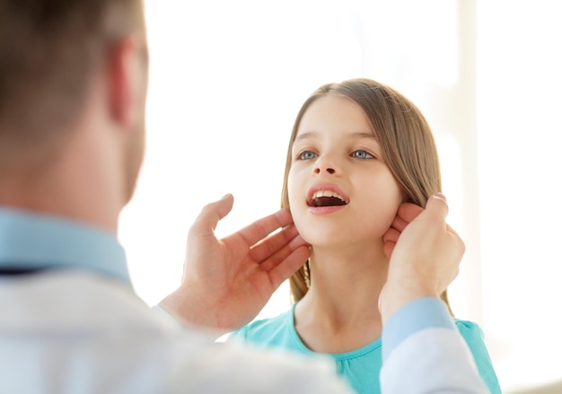 atención médica, niño y concepto médico: el médico masculino revisa los ganglios linfáticos de las niñas en el hospital