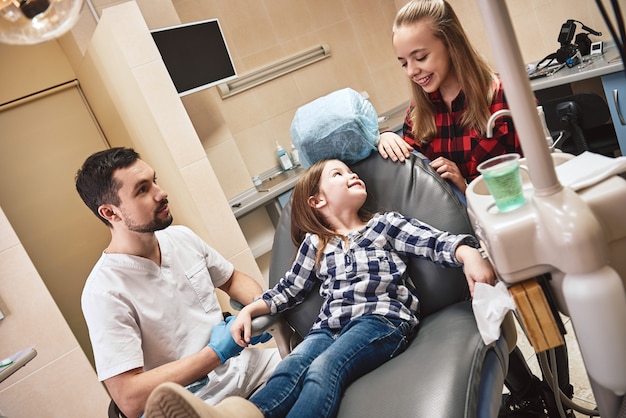 Atención premium toque personal hermosa niña sonriente en el consultorio dental esperando dental