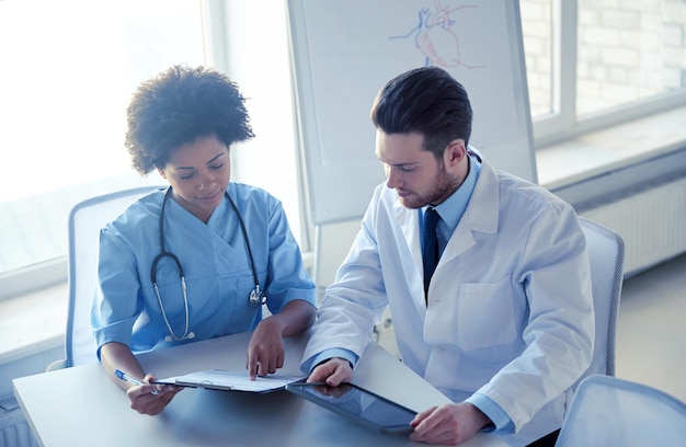 Foto atención de la salud, personas, tecnología y concepto de medicina - médico y enfermera con tablet pc y reunión de portapapeles y discutiendo algo en el hospital