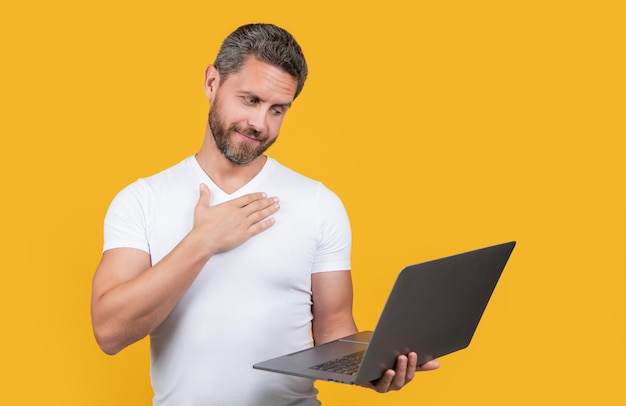 Foto atenciosamente, programador de homem no estúdio, programador de homem com laptop isolado em fundo amarelo