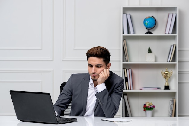 Atendimento ao cliente bonitão em terno de escritório com trabalho concentrado em computador