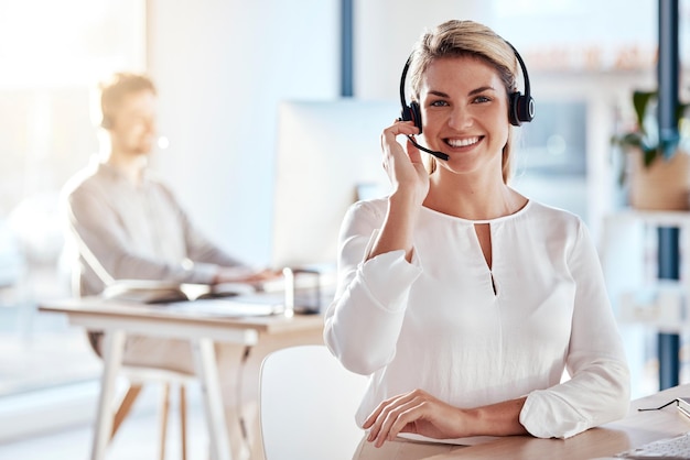 Atendimento ao cliente de retrato e sorriso com uma consultora trabalhando em seu escritório para suporte pós-venda Call center entre em contato conosco e crm com uma jovem funcionária consultando usando um fone de ouvido