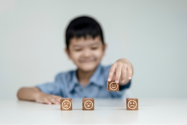 Atendimento ao cliente e conceito de satisfação, crianças mostram um feedback com ícone de rosto sorriso feliz cubo de madeira sorriso rosto para dar satisfação no serviço. classificação muito impressionado.