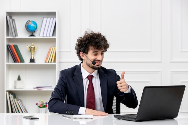 Atendimento ao cliente jovem bonito em terno de escritório com laptop e fone de ouvido feliz mostrando um bom sinal