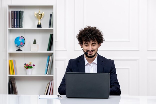 Atendimento ao cliente morena bonitinha em terno de escritório com laptop e fone de ouvido trabalhando e sorrindo