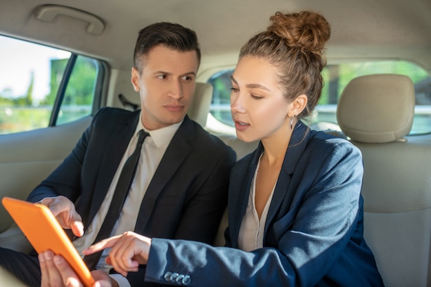 Atento hombre y mujer trabajando con tableta en coche