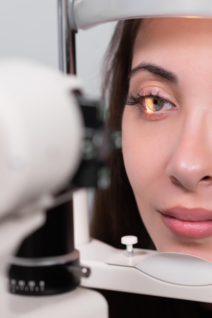 Foto atento optometrista examinando a una hermosa paciente con lámpara de hendidura en una clínica de oftalmología optometrista durante un examen en una clínica moderna revisión de la vista primer plano de una paciente