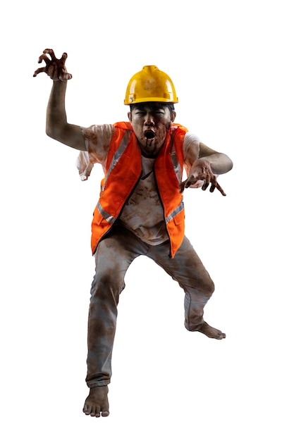 Un aterrador zombi trabajador de la construcción con sangre y heridas en su cuerpo caminando aislado sobre un fondo blanco.