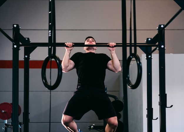 Athlet, der Calisthenics übt. Junger Mann, der Barmuskelübungen tut. Fitnessstudio. Fitness.