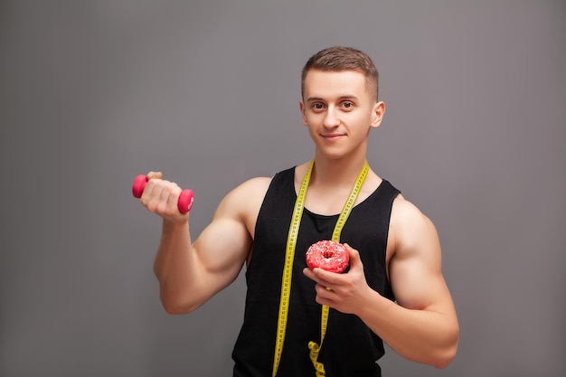 Athlet, der Hantel und Donut hält, deutet auf Training hin.