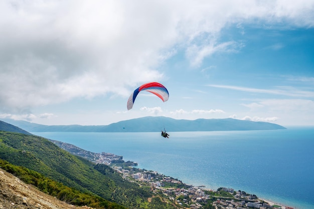 Athlet Paragliding vor dem Hintergrund eines bewölkten Himmels über den Bergen an einem Sommertag