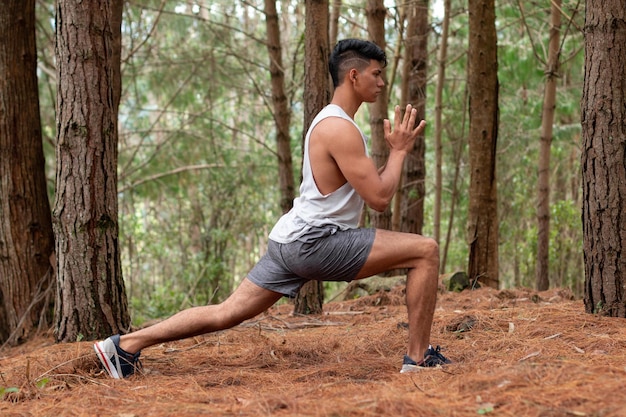 Athlet praktizieren Yoga die Krieger-Pose Gesunder Lebensstil Junger Erwachsener, der sich mit Bäumen im Hintergrund ausdehnt und Sport treibt