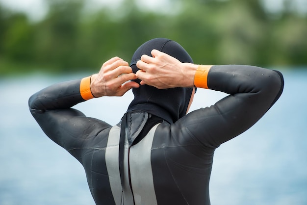 Athletenschwimmer zieht einen Neoprenanzug aus der hinteren Nahaufnahme an