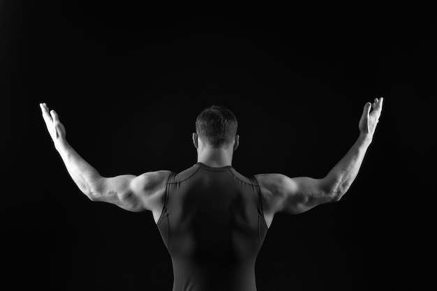 Athletic Bodybuilder Pose auf schwarzem Hintergrund isoliert Sport und Training Diät und Fitness Mann mit muskulösen Körper und Rücken Coach Sportler in Weste