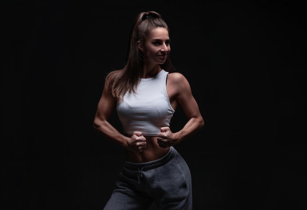 Athletic Fitness Frau posiert im Studio auf dunklem Hintergrund Foto einer attraktiven Frau in modischer Sportbekleidung Sport und gesunder Lebensstil