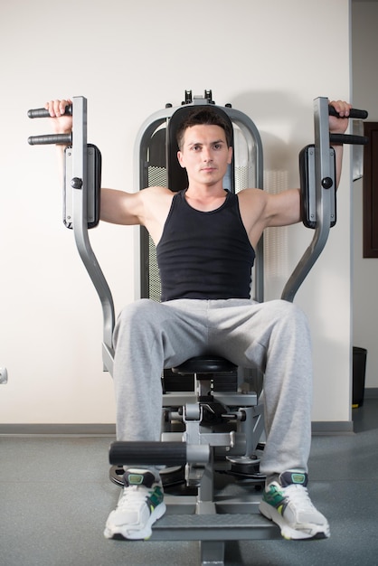 Athletisch gepumpter Mann beschäftigt sich mit Trainingsgeräten im Fitnessstudio