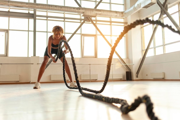 Foto athletische afroamerikanische frau in sportuniform trainiert morgens im fitnessstudio, das mädchen winkt